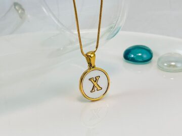 Dije dorado circular nácar letra X